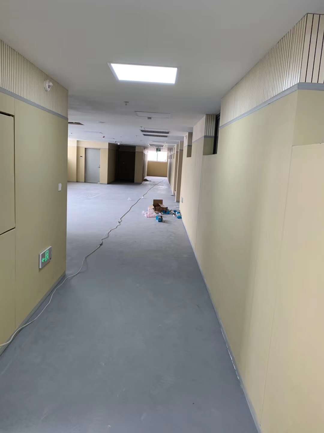 办案区走廊米色防撞软包墙面安装实景，上部搭配木条吸音板装饰，适用于审讯室留置室防撞防自伤装修